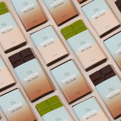 Matcha Union dark and white matcha chocolate bars arranged diagonally, with partially unwrapped bars revealing dark brown and matcha-green chocolate.