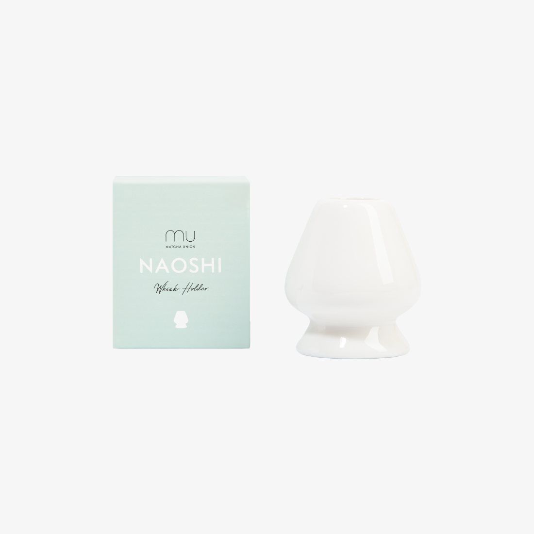 White ceramic Matcha Union whisk holder beside its mint-green Naoshi box, shaped to keep bamboo whisk prongs fanned out between uses.