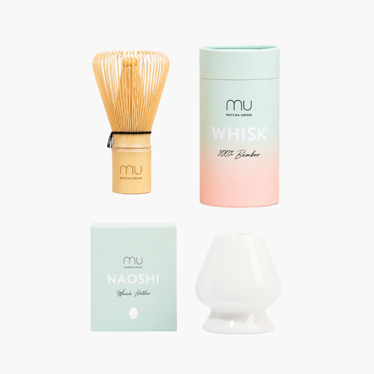 Matcha Union 100-prong bamboo whisk and white ceramic whisk holder displayed beside their pastel packaging.