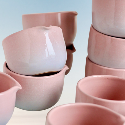 Handmade Sakura Matcha Bowls stacked together, showing variations in their pink gradient glaze, rounded shapes and pouring spouts.